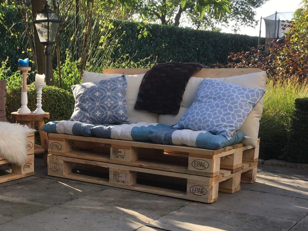 Stijlvolle pallet bank in zomerse tuinomgeving, perfect voor ontspanning en buiten genieten