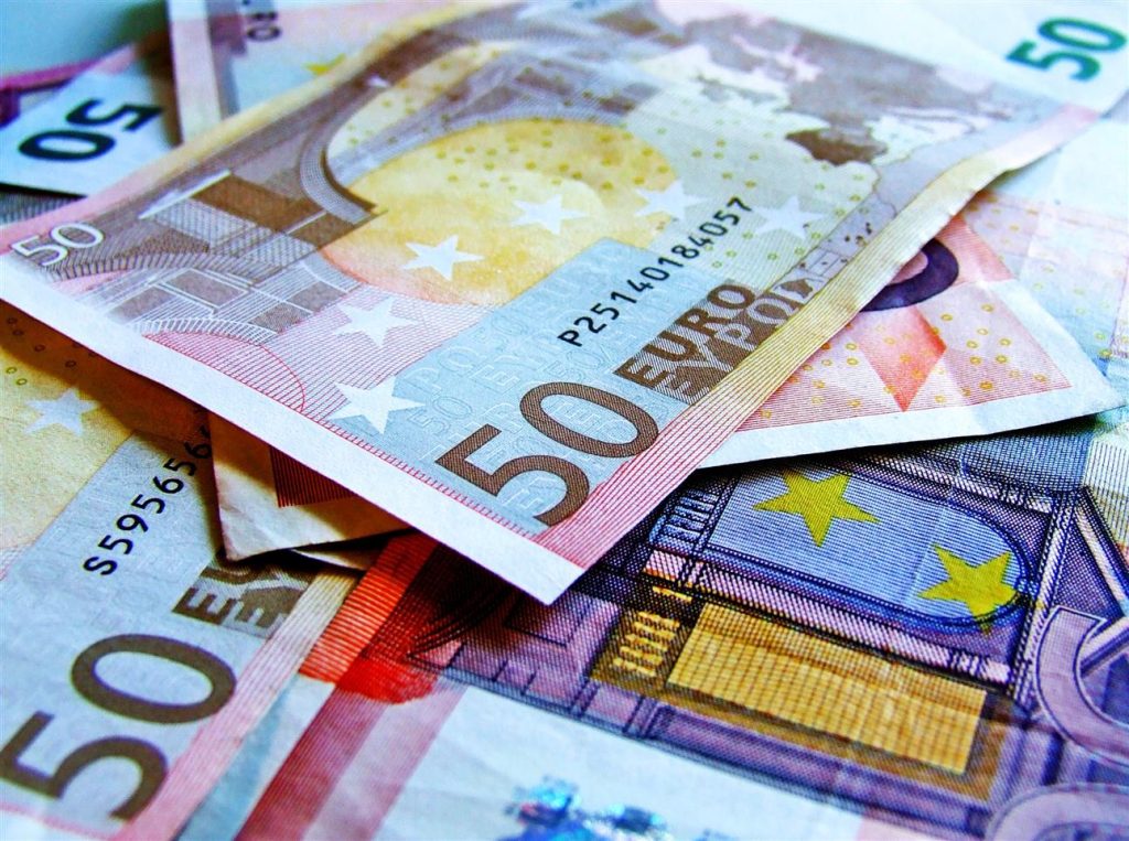 Euro bankbiljetten en munten op een tafel met financiële grafieken ter illustratie van bruiloftsfinanciering voor postpandemi