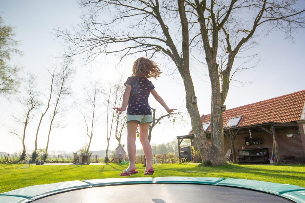 Kinderen spelen op een trampoline in de tuin, een geweldige toevoeging voor gezondheid en plezier van het hele gezin